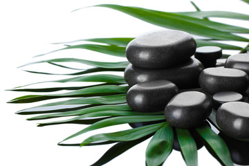 Spa stones on green palm leaf on grey background