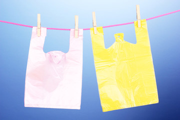 Cellophane bags hanging on rope on blue background