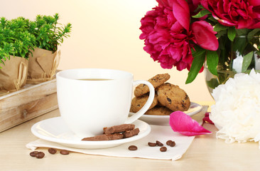 cup of coffee, cookies, chocolate and flowers on table in cafe
