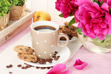 cup of coffee, cookies, apple and flowers on table in cafe