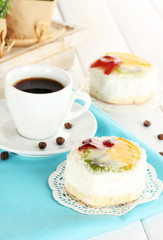 cup of coffee and sweet cakes with fruits on wooden table