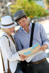 Trendy young couple in town with touristic map