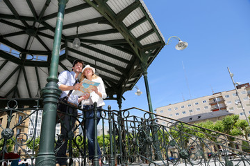 Young couple standing in gazebo reading touristic map