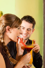 Young couple drinking cocktails in bar or restaurant