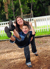 Mom pushing son on swing