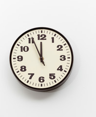 Brown clock on white office wall near noon