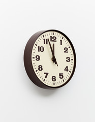 Brown clock on white office wall near noon
