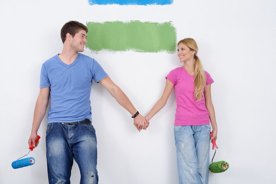happy couple paint wall at new home