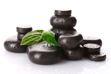 Spa stones with drops and green leaves isolated on white