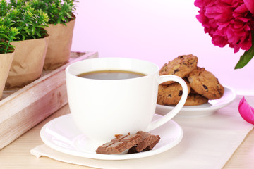 cup of coffee, cookies, chocolate and flowers on table in cafe