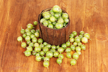 Green gooseberry in wooden cup on wooden background