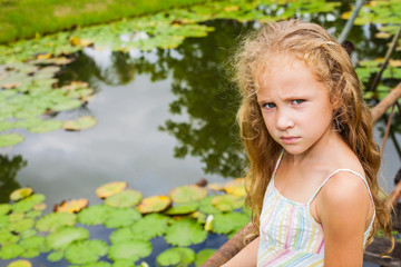 sad little girl near a pond