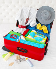 Red travel suitcase packed for vacation with personal belongings