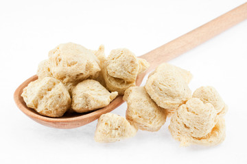soya flakes in wooden spoon on white background