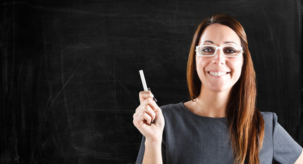 Smiling teacher in front of an empty blackboard