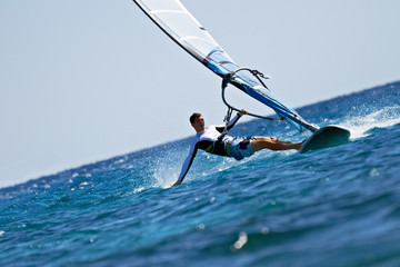 Young man surfing the wind in splashes of water