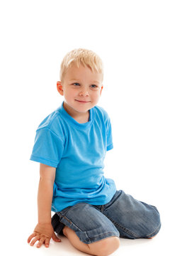 Happy little boy sitting on knees isolated on white