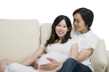 Obraz premium asian man and his pregnant wife sitting on the sofa