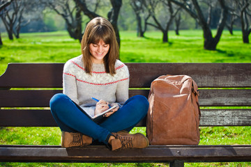 girl sitting in a park and doing her homework