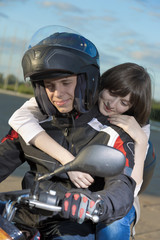 Fototapeta na wymiar The girl embraces the young man on a motorcycle