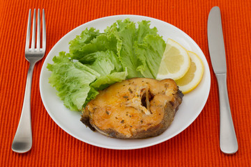 fish with salad and lemon on the white plate