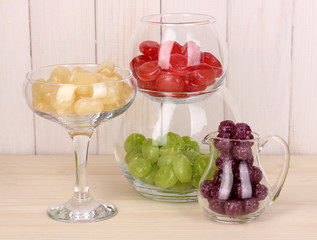 Color candies in glasses on wooden background