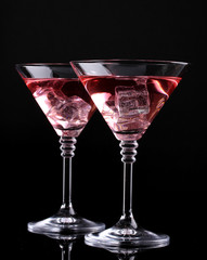 Red cocktail in martini glasses isolated on black
