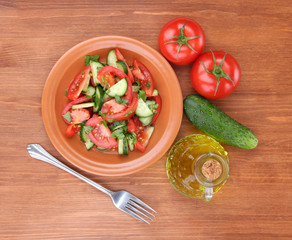 Fresh salad with tomatoes and cucumbers on wooden background