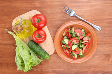 Fresh salad with tomatoes and cucumbers on wooden background