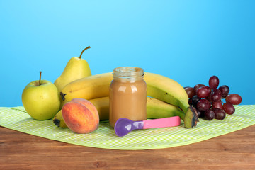 Jar with fruit baby food, spoon and fruits