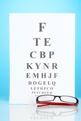 Eyesight test chart with glasses on blue background close-up