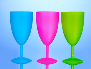 Bright plastic goblets on blue background