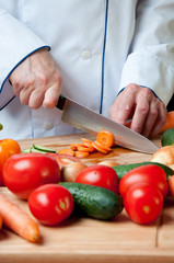 Chef chopping fresh carrot, close-up