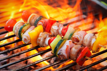 barbecue with flames and vegetable spit