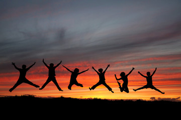 Fototapeta na wymiar silhouette of teenagers jumping in sunset for fun
