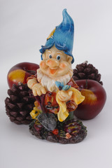 Gnome in a hat and a shovel with candle apple