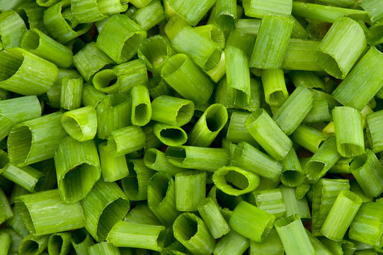 close up image of chopped spring onions on a white background