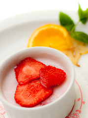 Italian dessert panna cotta on white plate decorated wth orange