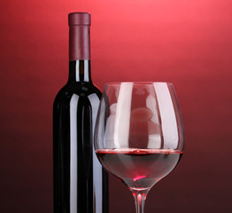 Bottle of great wine and wineglass on red background