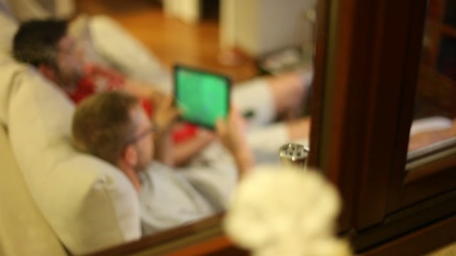 Boys on sofa watching tv and playing with tablet