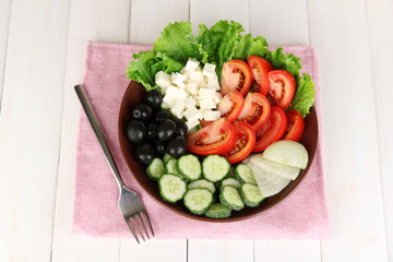 tasty Greek salad on white wooden background