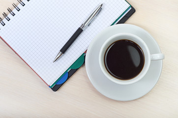 Coffee cup with note book on table