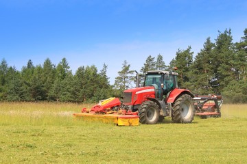 Obraz premium Red tractor mowing the meadow, Czech Republic