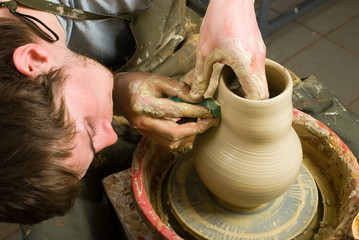 hands of a potter, creating an earthen jar of white clay