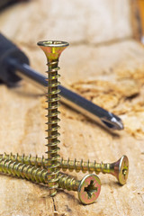 Macro image of a screwdriver and screws on a wooden surface