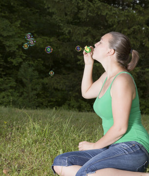 Cute girl blowing colorful bubbles outdoors