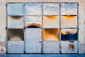 Old metal and glass warehouse door with sun reflections