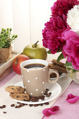 cup of coffee, cookies, apples and flowers on table in cafe