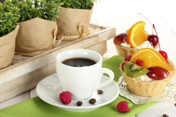 cup of coffee and sweet cakes with fruits on wooden table