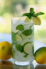 A glass of mojito/ caipirinha  with lime slices and mint